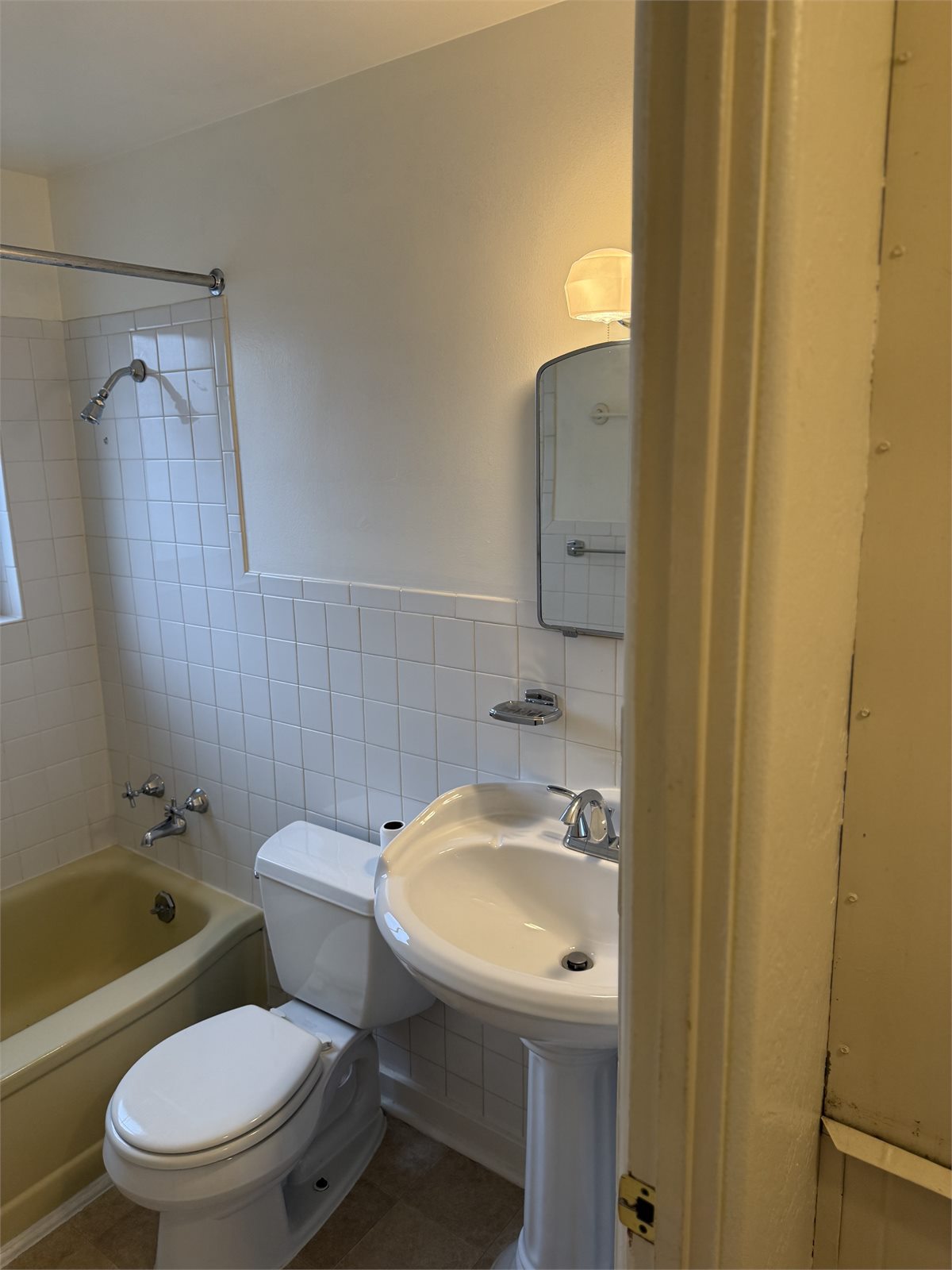 Bathroom with bathtub and shower, toilet, pedestal sink, and tiled walls