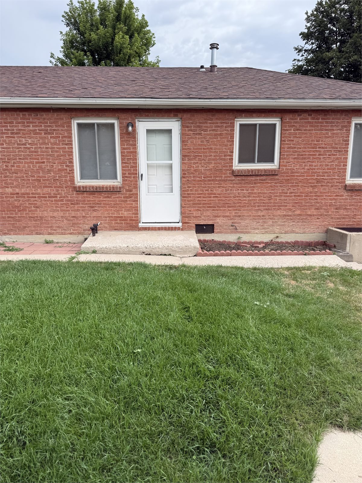 Front exterior of the brick four-unit property with lawn