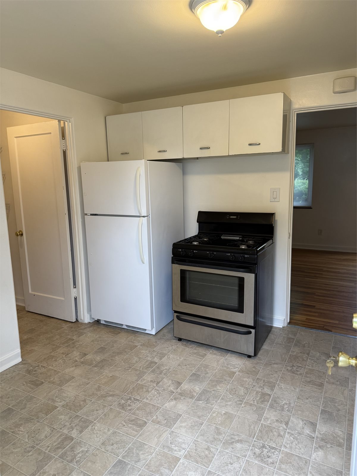 Kitchen with refrigerator, gas range, upper cabinets, and durable flooring