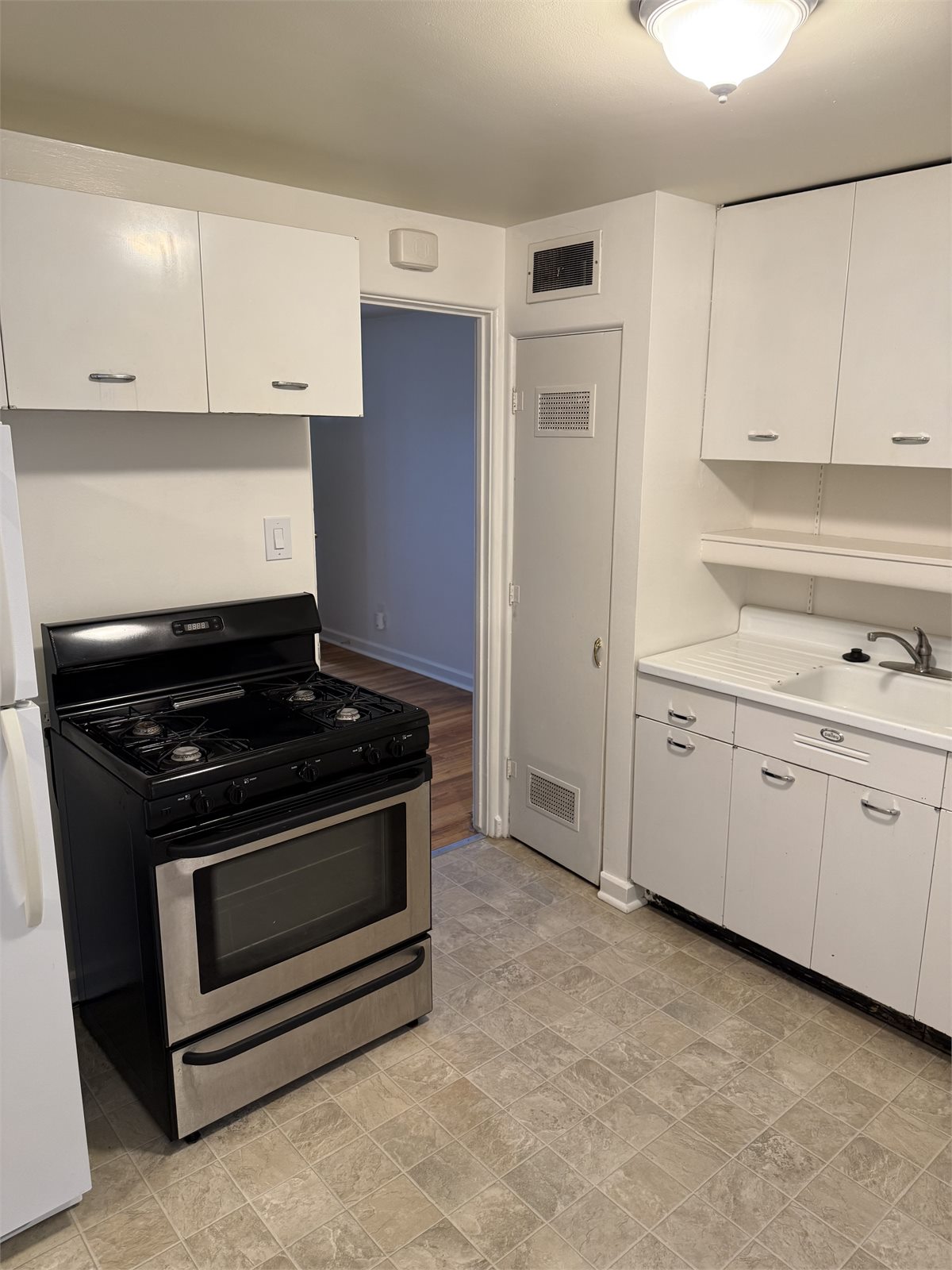 Second kitchen view showing the sink, cabinetry, gas range, and open floor area