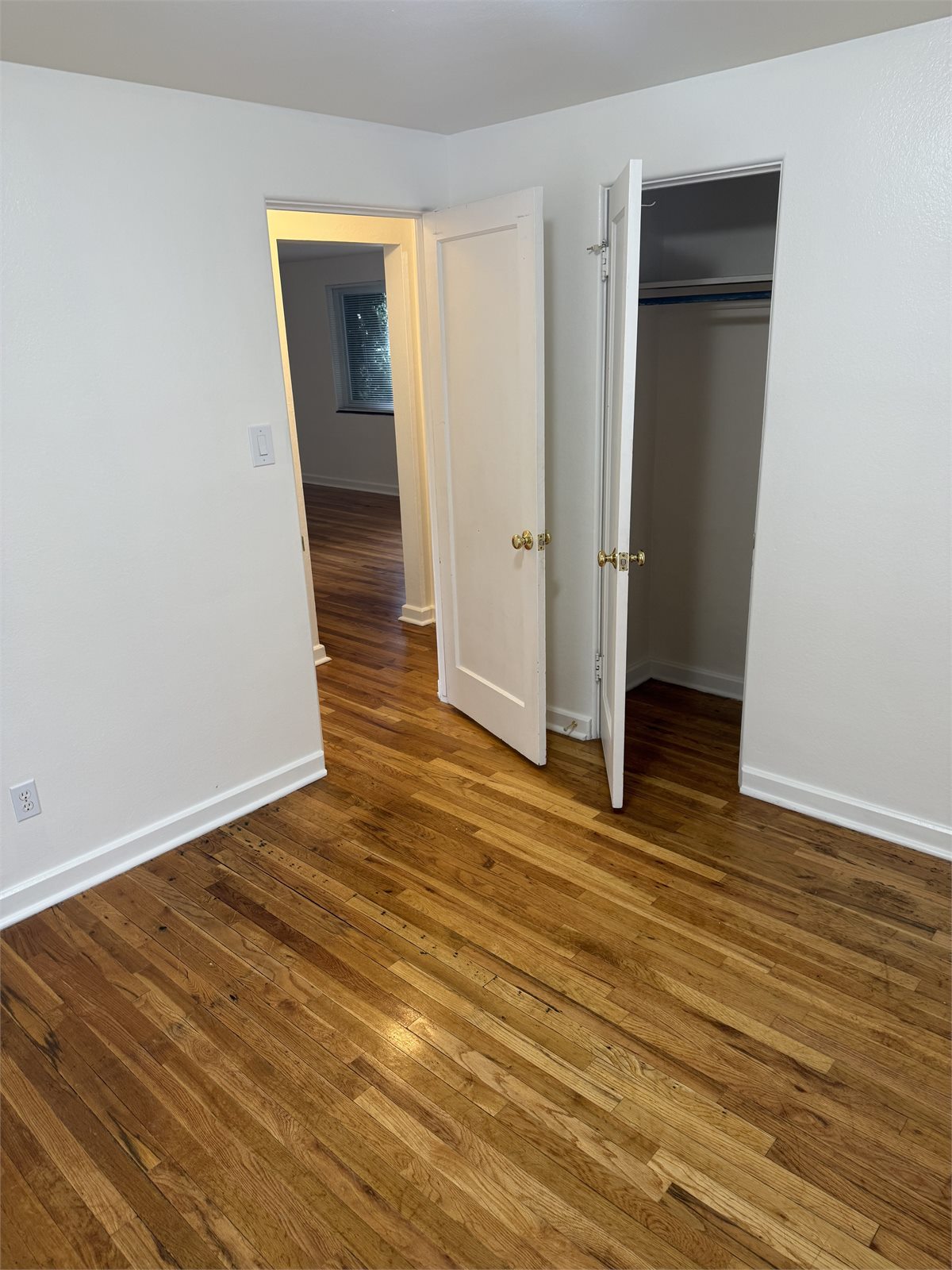 Second bedroom with hardwood floors, closet, and doorway to the hall